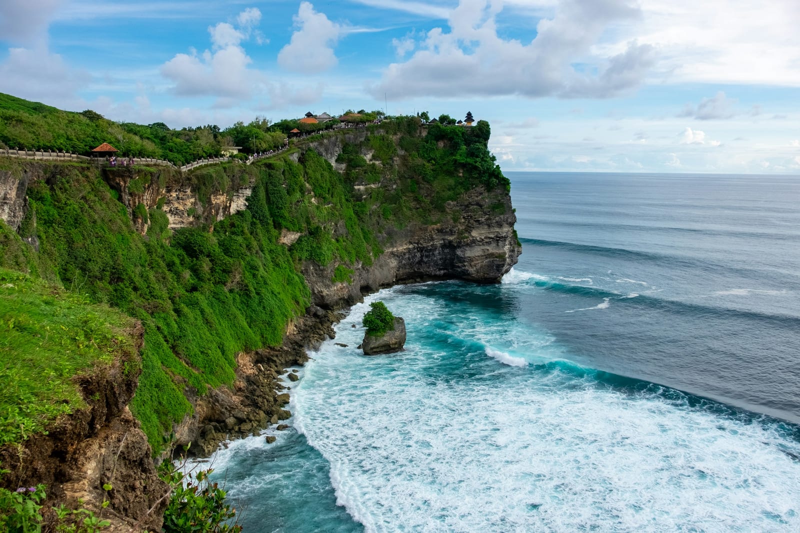 A green sea cliff above waves along the coast of Bali.
