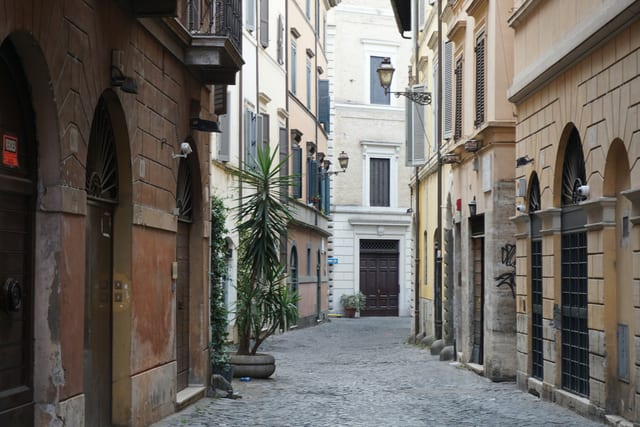A quiet cobblestone lane lined with potted plants in Trastevere.