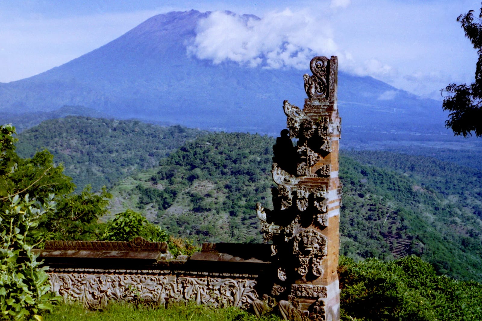 A Balinese split gate stands before a forested volcano.