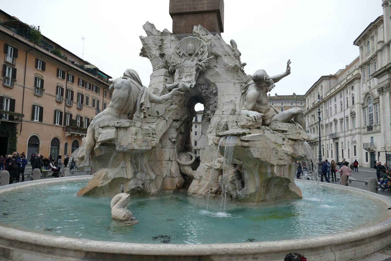 A river-god figure of Bernini's Fountain of the Four Rivers leans out over the water, the palazzi of Piazza Navona behind.