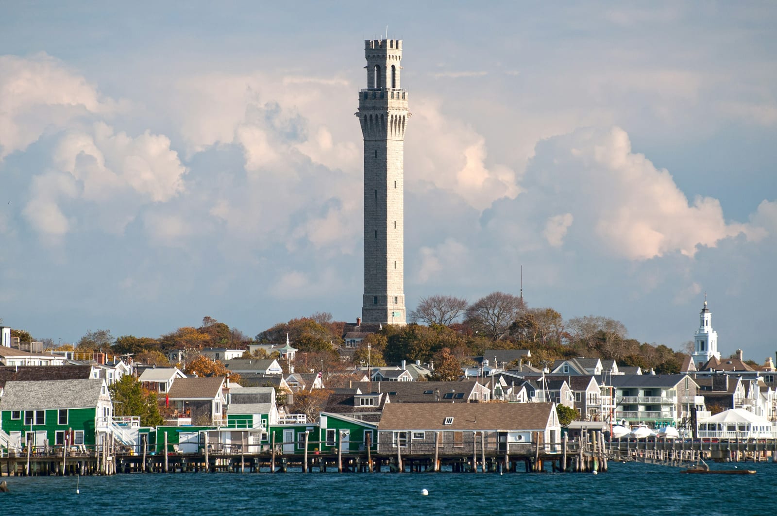 The Pilgrim Monument towering over Provincetown's harborfront village, seen from the water
