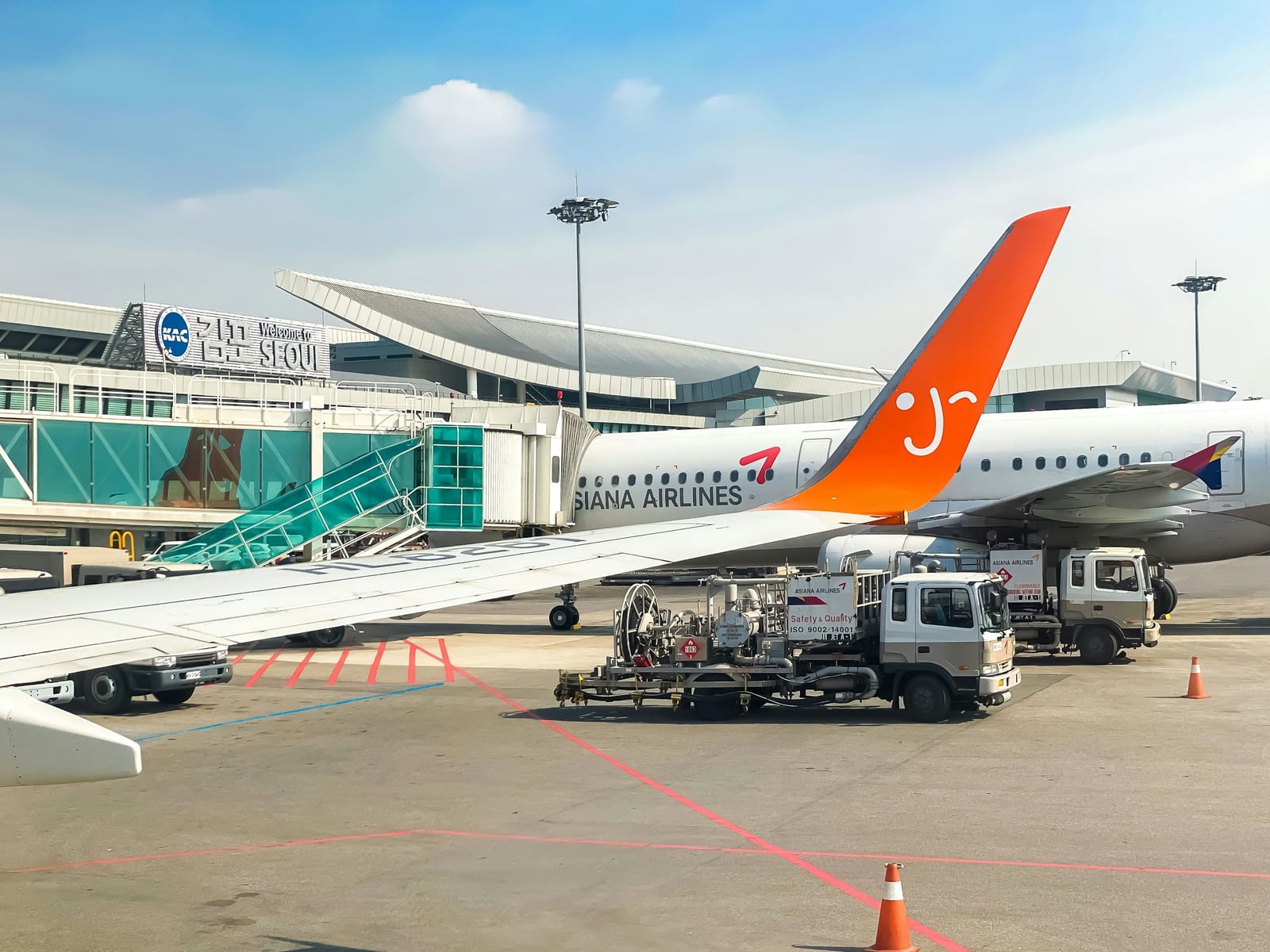A passenger airplane is parked beside a Seoul airport terminal on a sunny day.