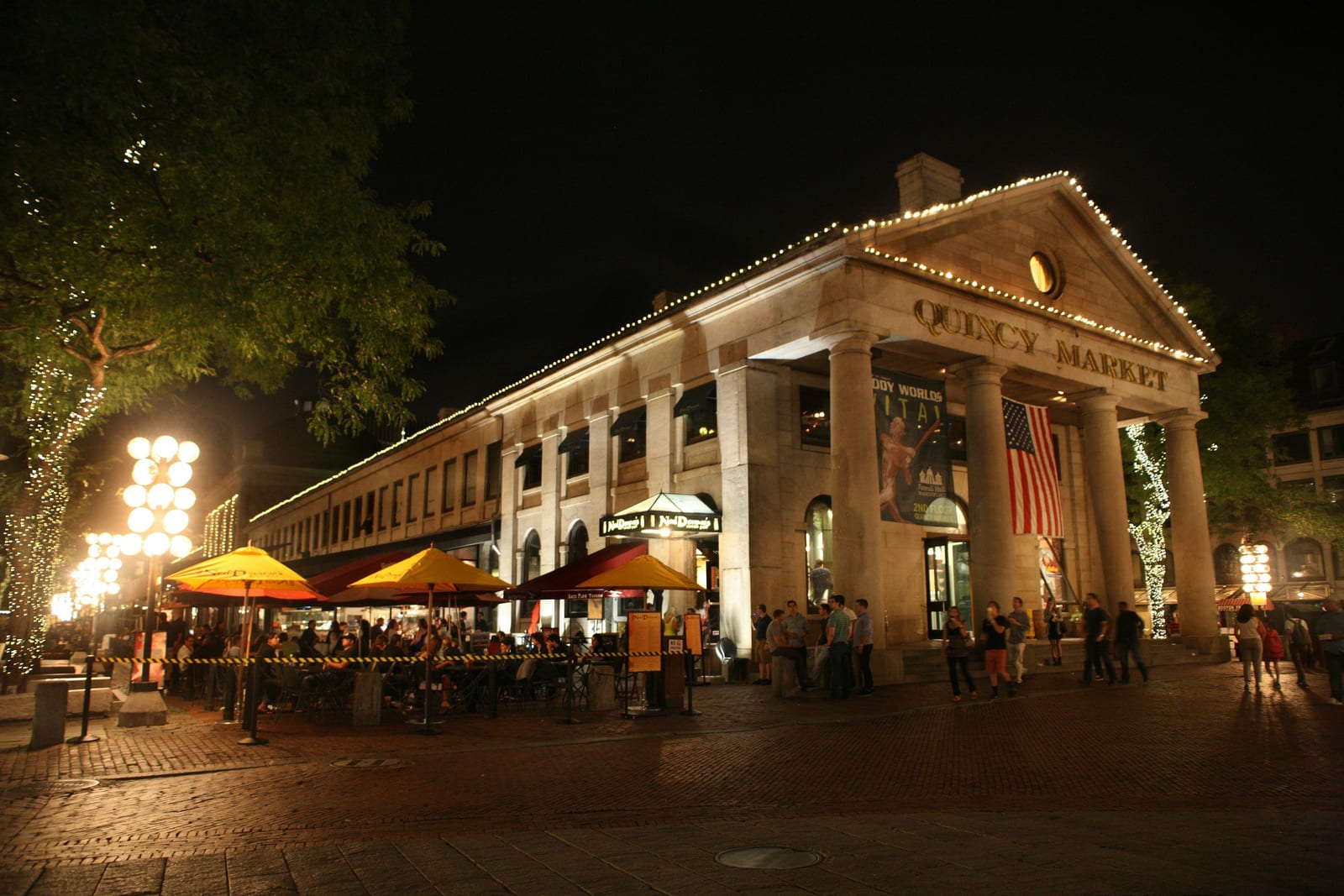 Faneuil Hall and Quincy Market lit up with holiday lights and a large Christmas tree.