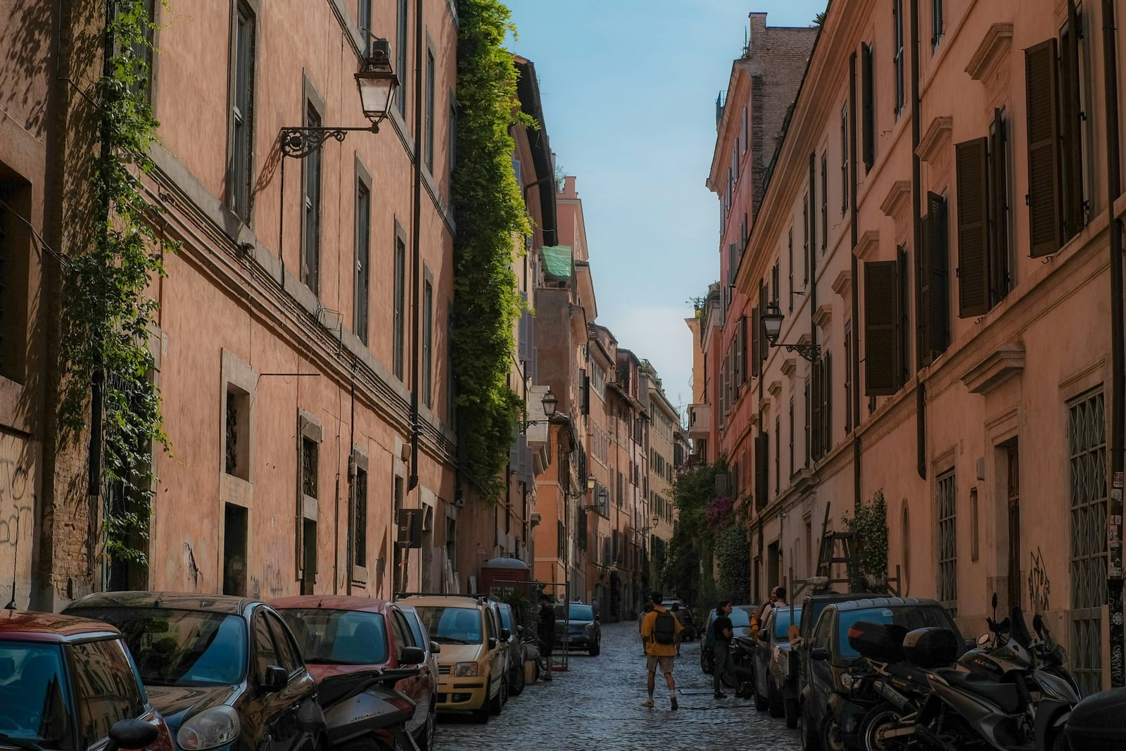 A quiet cobblestone lane lined with potted plants in Trastevere.