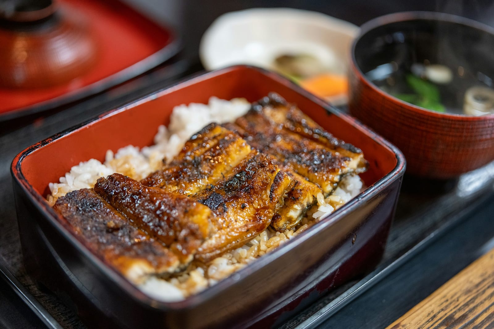 A lacquer box of unadon, grilled eel glazed over rice, with miso soup and pickles.