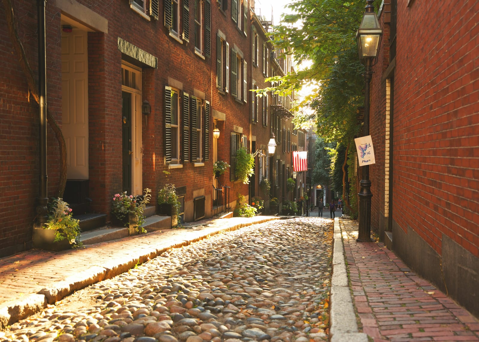 Acorn Street on Beacon Hill, cobblestones and brick row houses with American flags