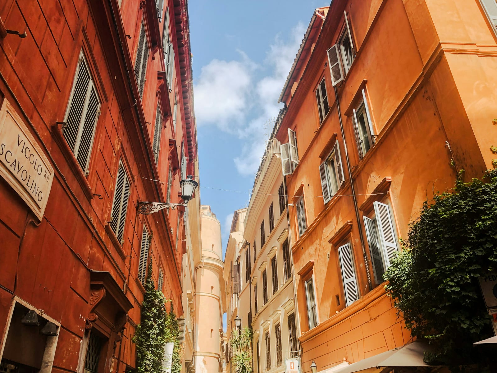 A sunlit, ivy-draped cobbled lane in Trastevere, Rome.