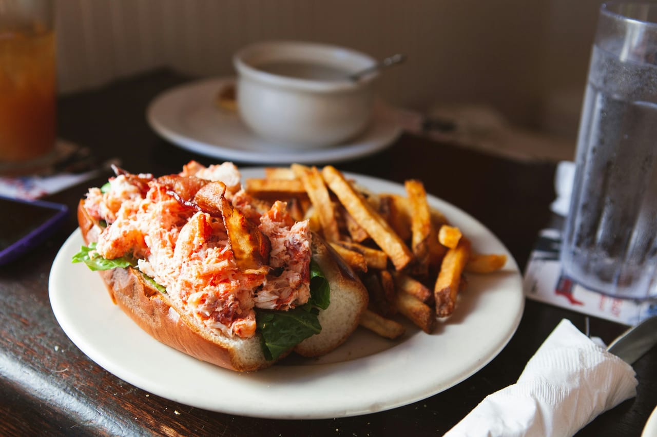 A lobster roll overflowing with chunks of lobster meat in a toasted split-top bun.