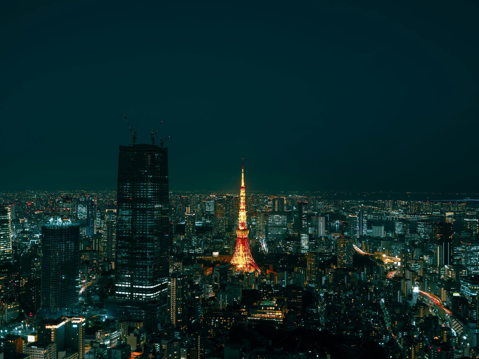 Tokyo Tower glowing over the city skyline with Mount Fuji at sunset