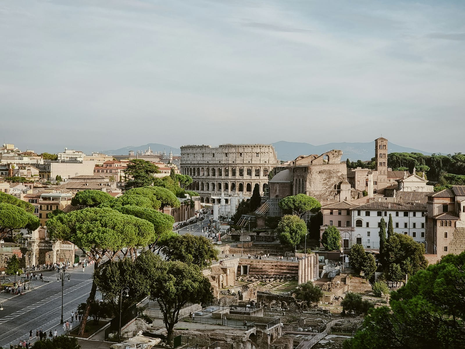 A rooftop terrace over Roman buildings in the evening light.