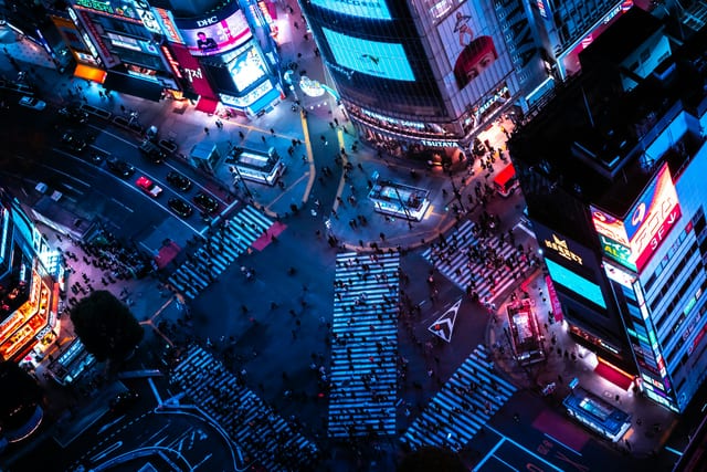 Shibuya Crossing lit up at night from above