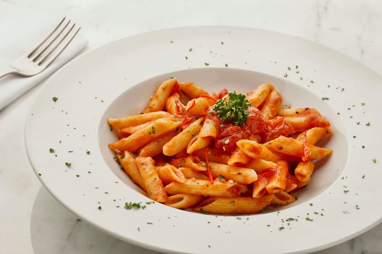 A plate of fresh pasta with tomato sauce at an Italian restaurant table.