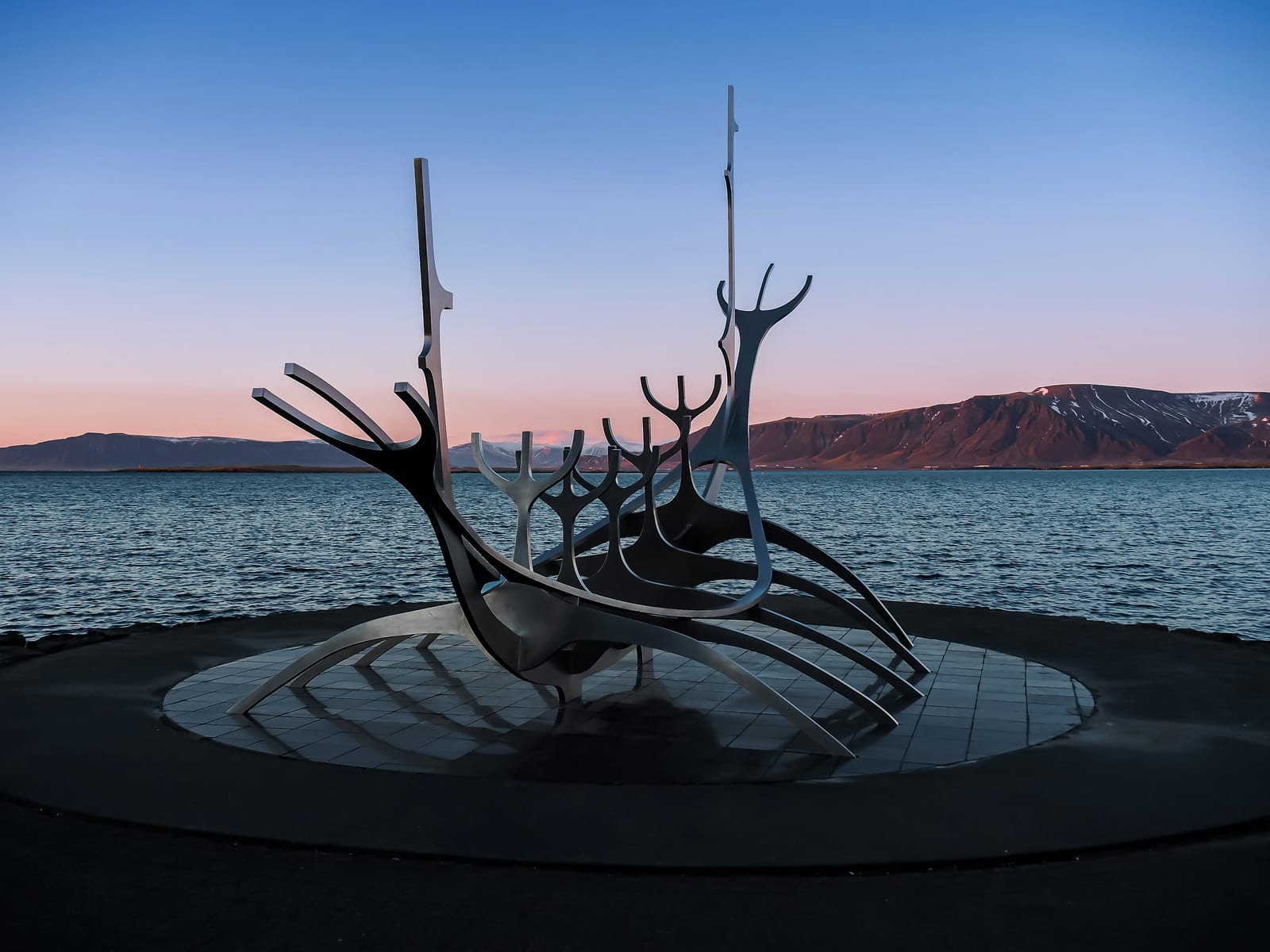 The Sun Voyager sculpture stands beside the water with a mountain ridge across the bay.