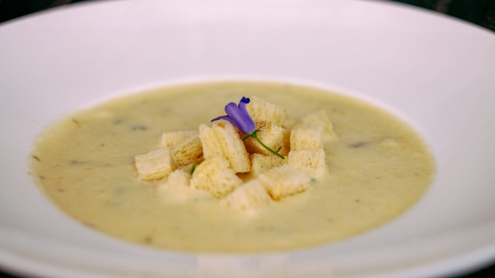 A bowl of creamy New England clam chowder with oyster crackers on the side.