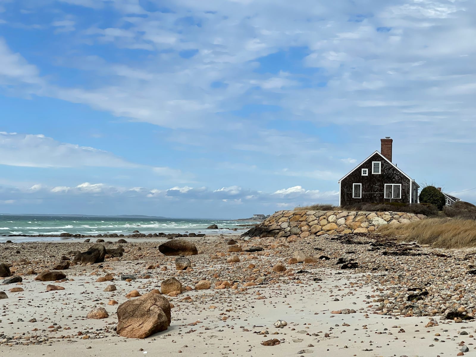 A house sitting on top of a sandy beach next to the ocean