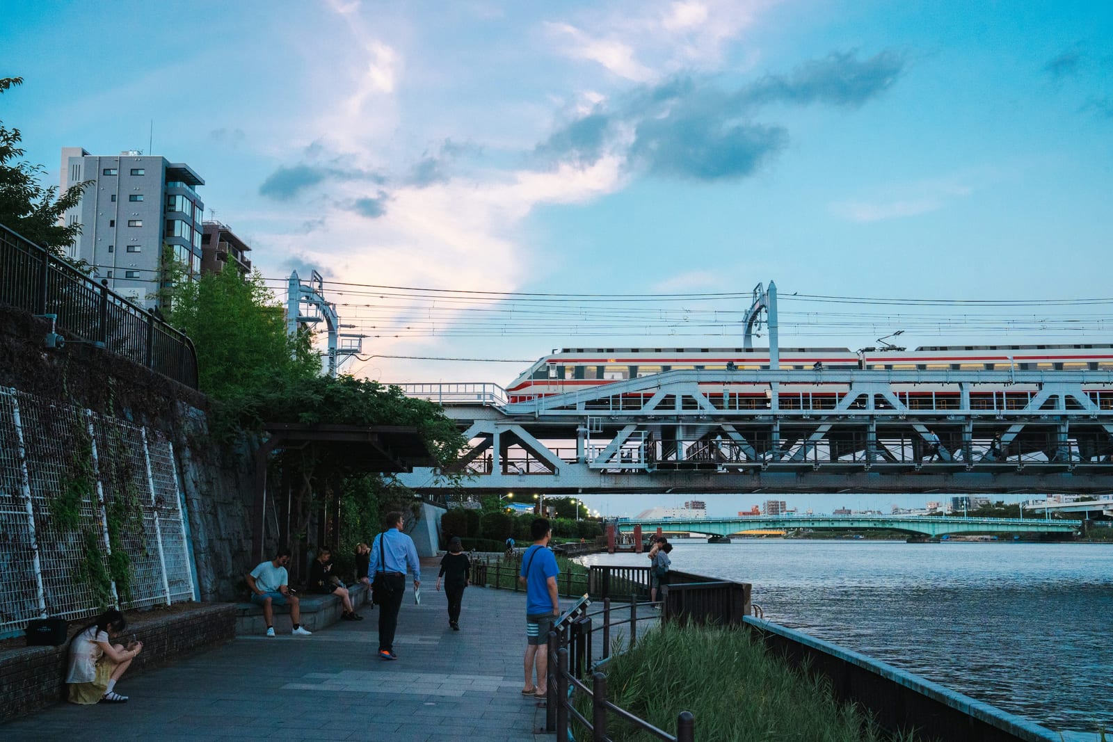 The Sumida River by Asakusa at dusk, with a train crossing the bridge.