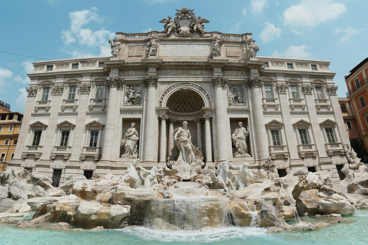 The Trevi Fountain's tritons and rearing sea horses spill into its turquoise basin below the palace facade.