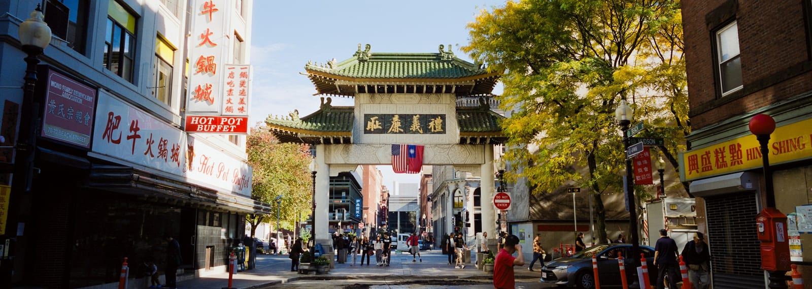 A colorful Chinatown gate framing a city street at dusk.