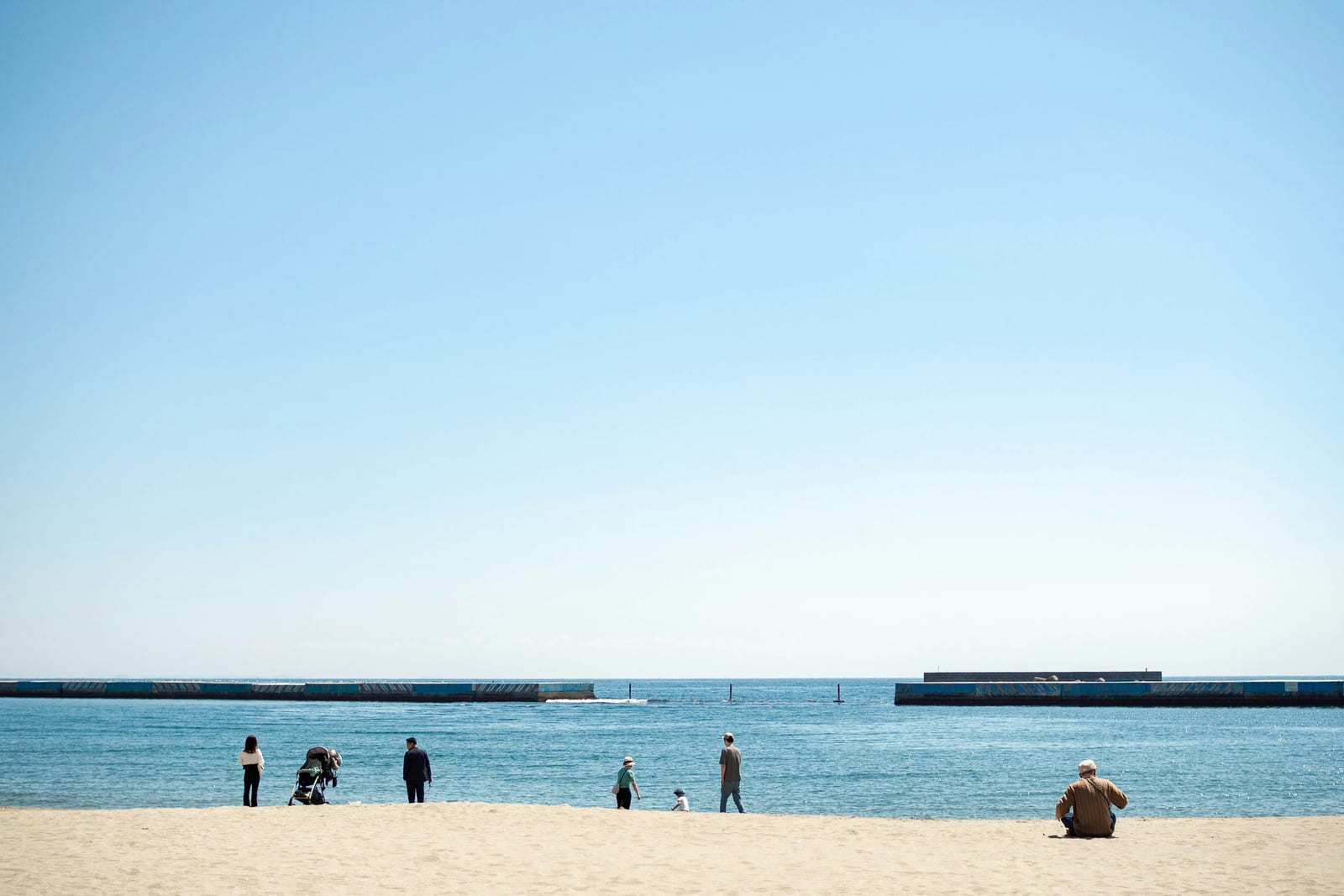 Atami's Sun Beach in the middle of town, with people on the sand and the sea beyond.