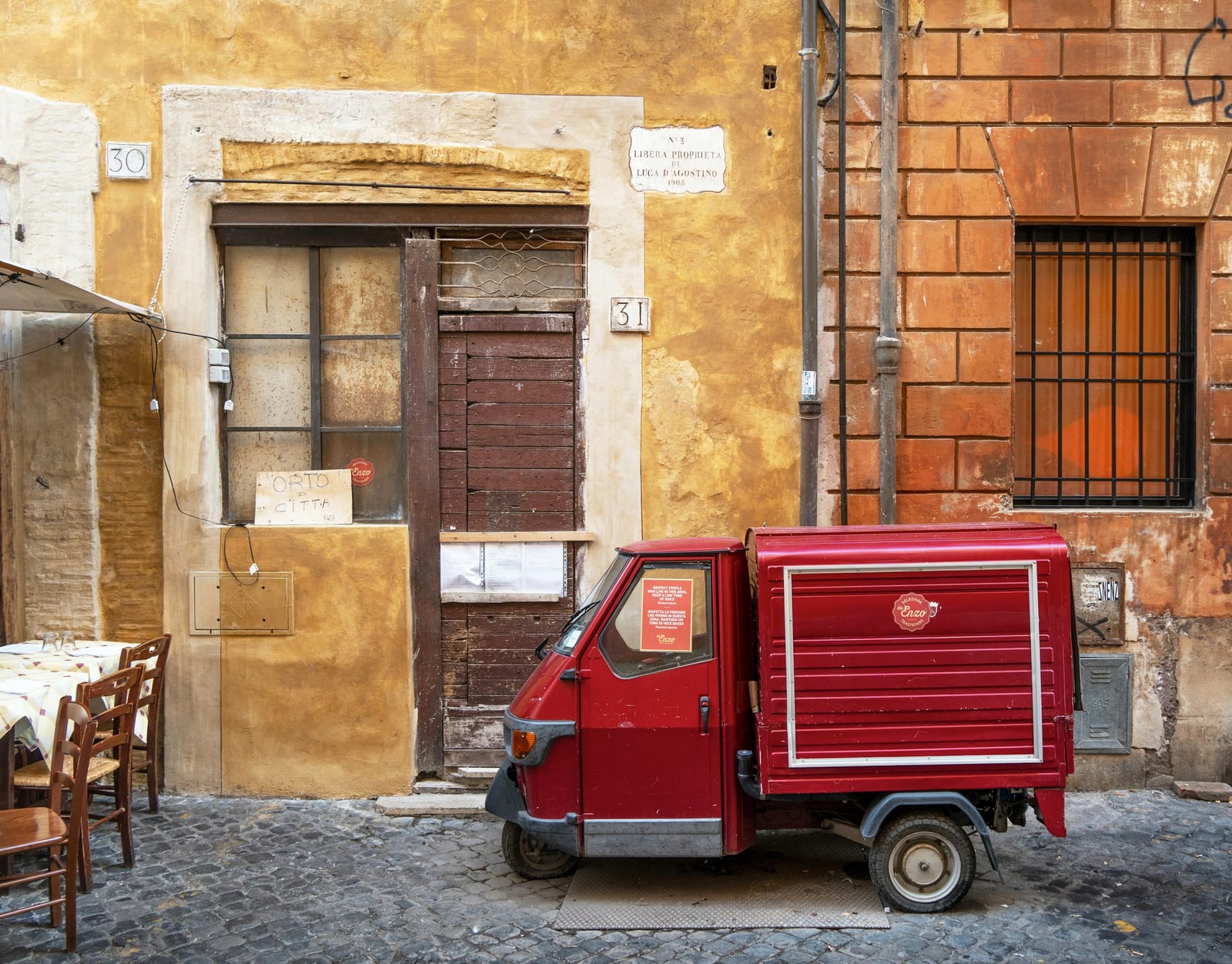 A quiet cobbled lane of warm ochre buildings in the historic center of Rome.