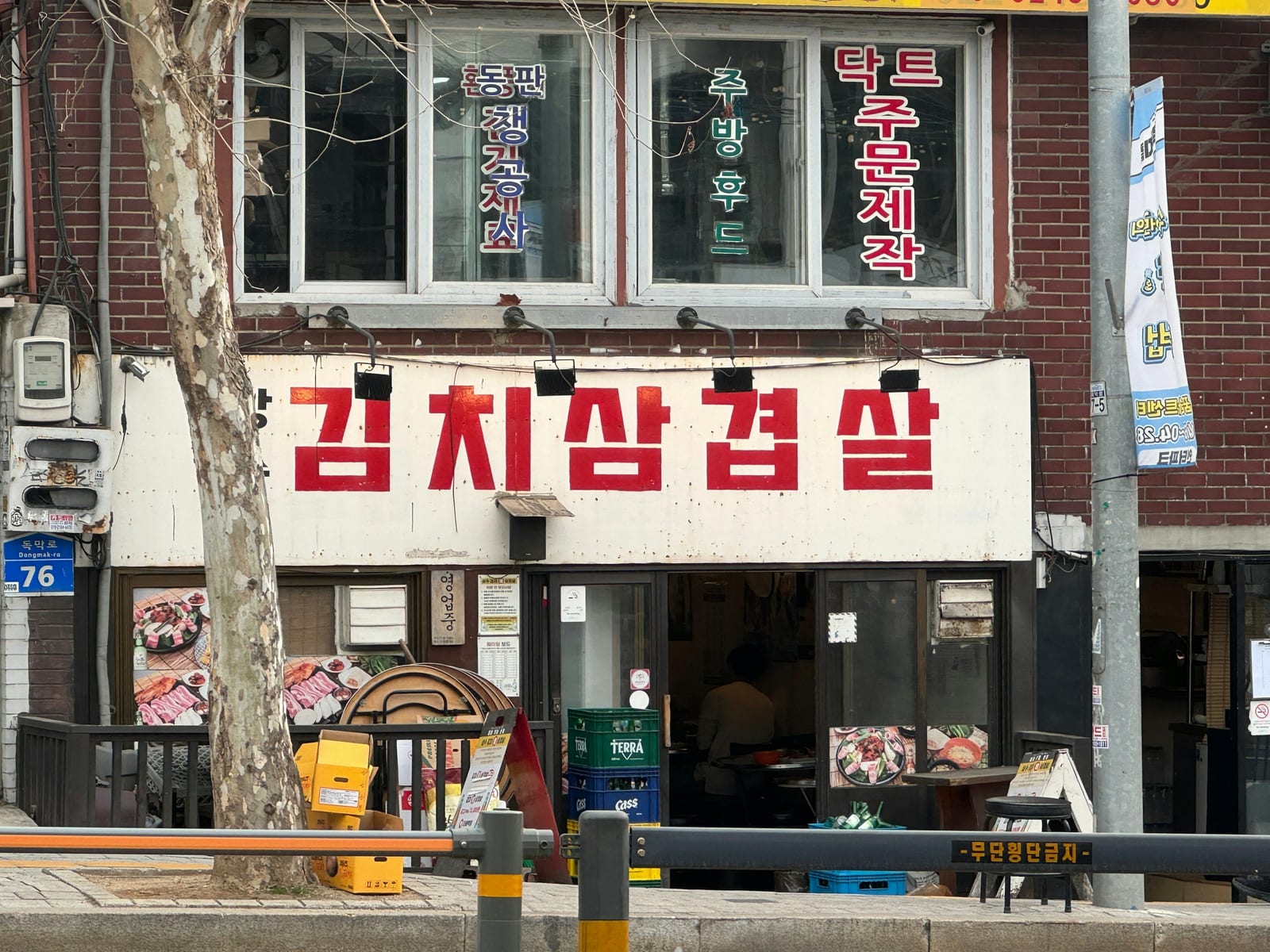 A Korean restaurant storefront with a large kimchi pork belly sign on a Seoul street.