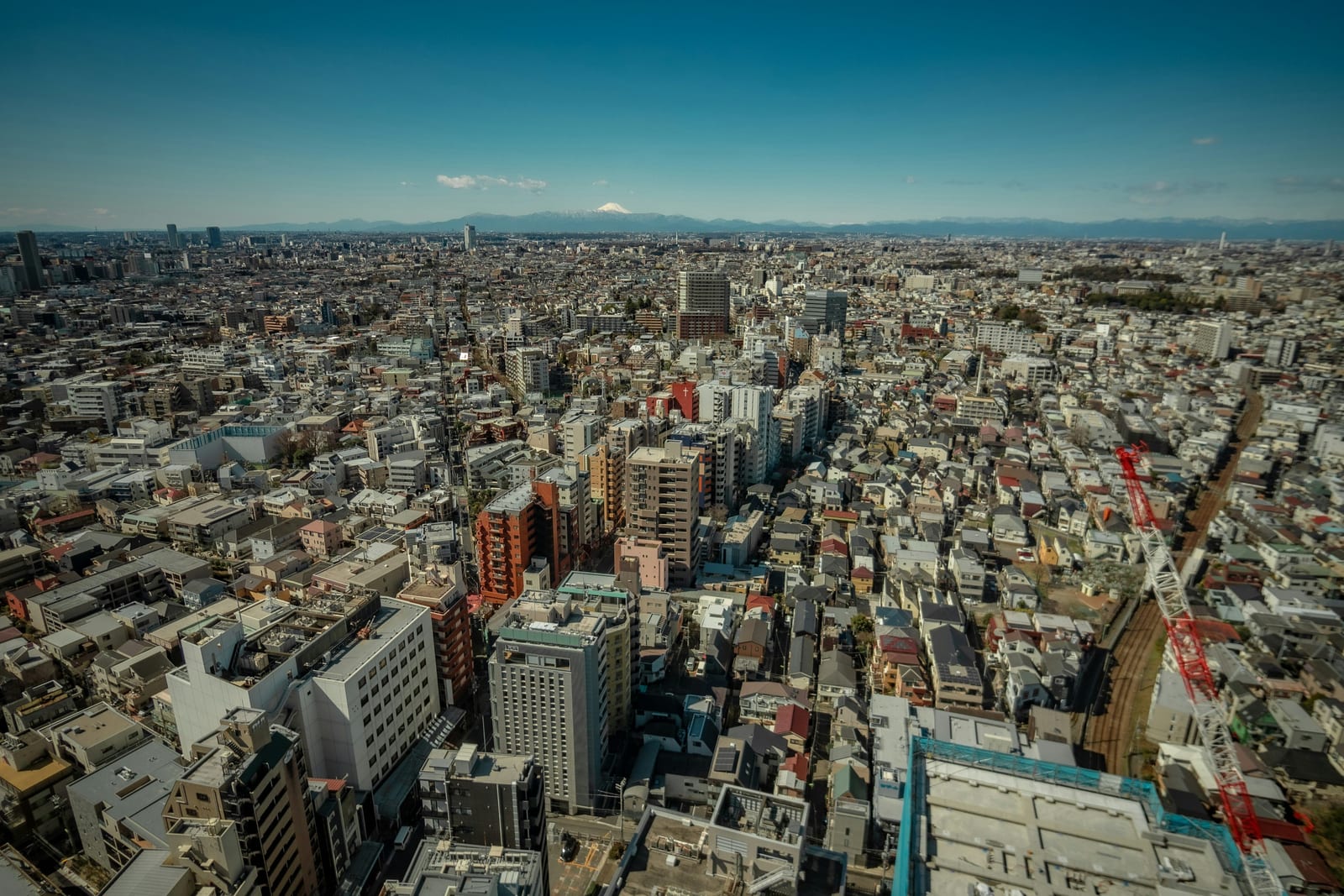 Snow-capped Mt. Fuji beyond the Tokyo skyline on a clear winter day.
