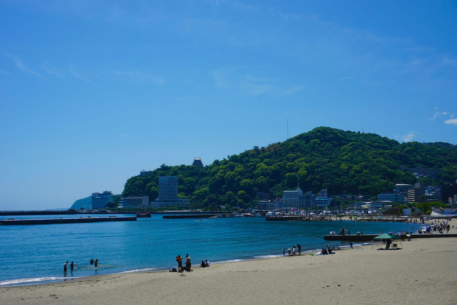 The resort town of Atami curving around its bay, with a castle on the green headland.
