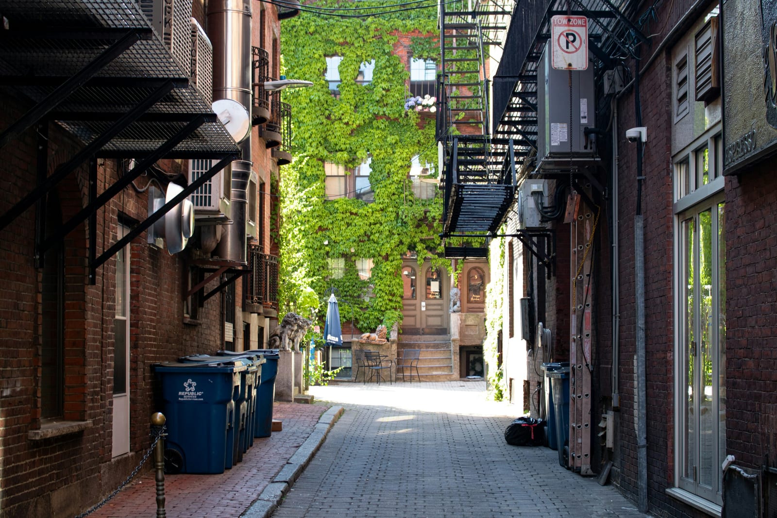 Narrow street in Boston's North End with brick buildings and restaurant awnings