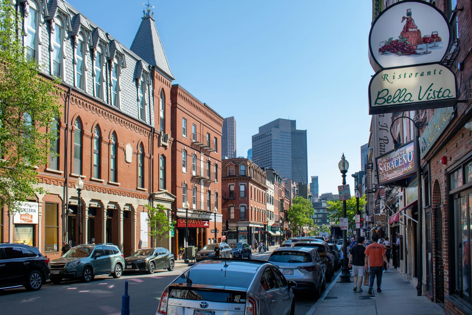 Narrow street in Boston's North End with brick buildings and restaurant awnings.