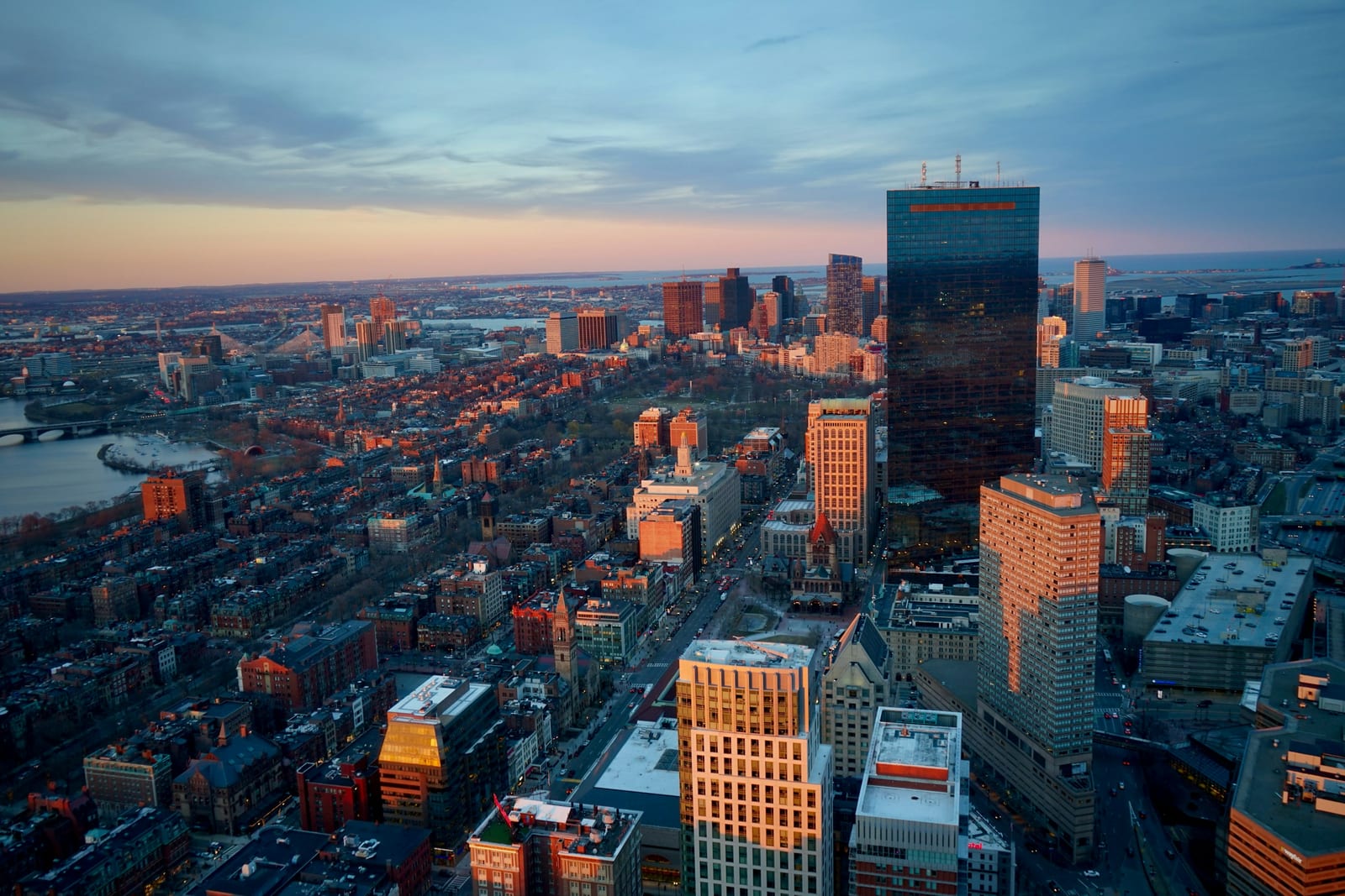 Golden-hour aerial view of Boston's South End, the Cathedral of the Holy Cross rising above Victorian rooftops