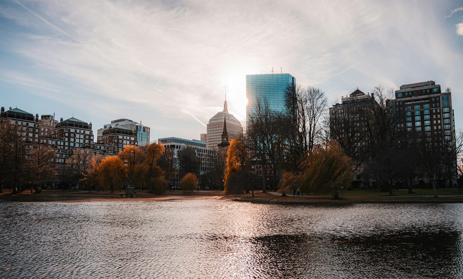 Boston Public Garden ablaze with red and gold autumn foliage reflected in the lagoon.