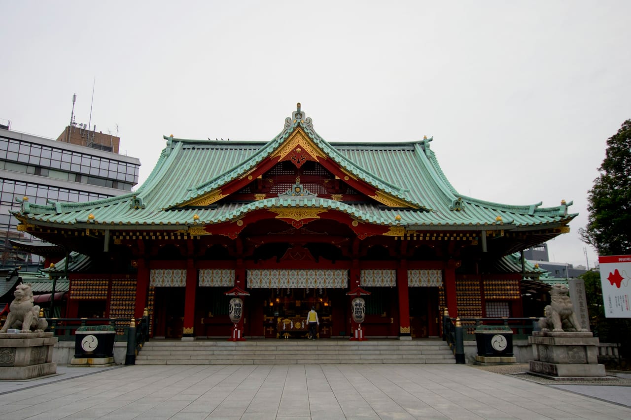 Kanda Myojin's ornate vermilion gate glows under its lanterns at dusk, the shrine's name lit across the paper globes.