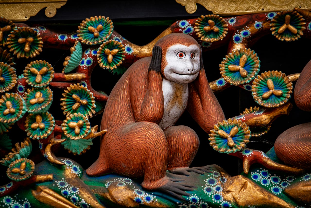 A gilded and painted monkey carving on the Sacred Stable at Nikko Toshogu, part of the shrine's famous monkey panels.