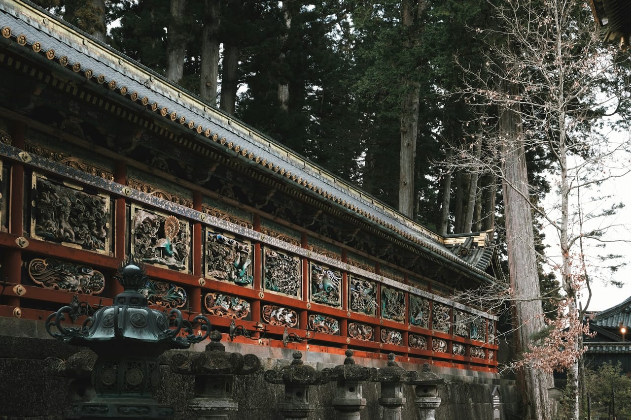 The lavishly gilded Yomeimon Gate of Nikko Toshogu shrine, carved and painted in gold, stands against a clear blue sky.