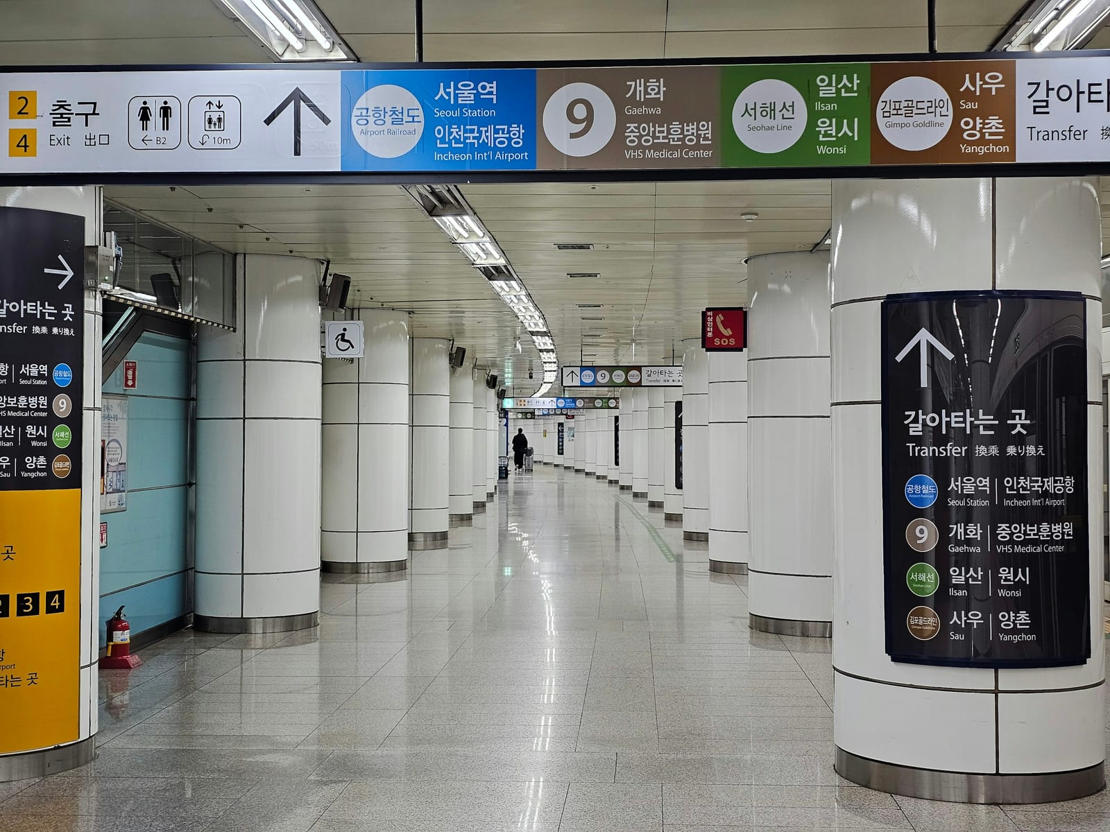 Bright Seoul station corridor with transfer signs, tiled walls, and a mostly empty walkway.