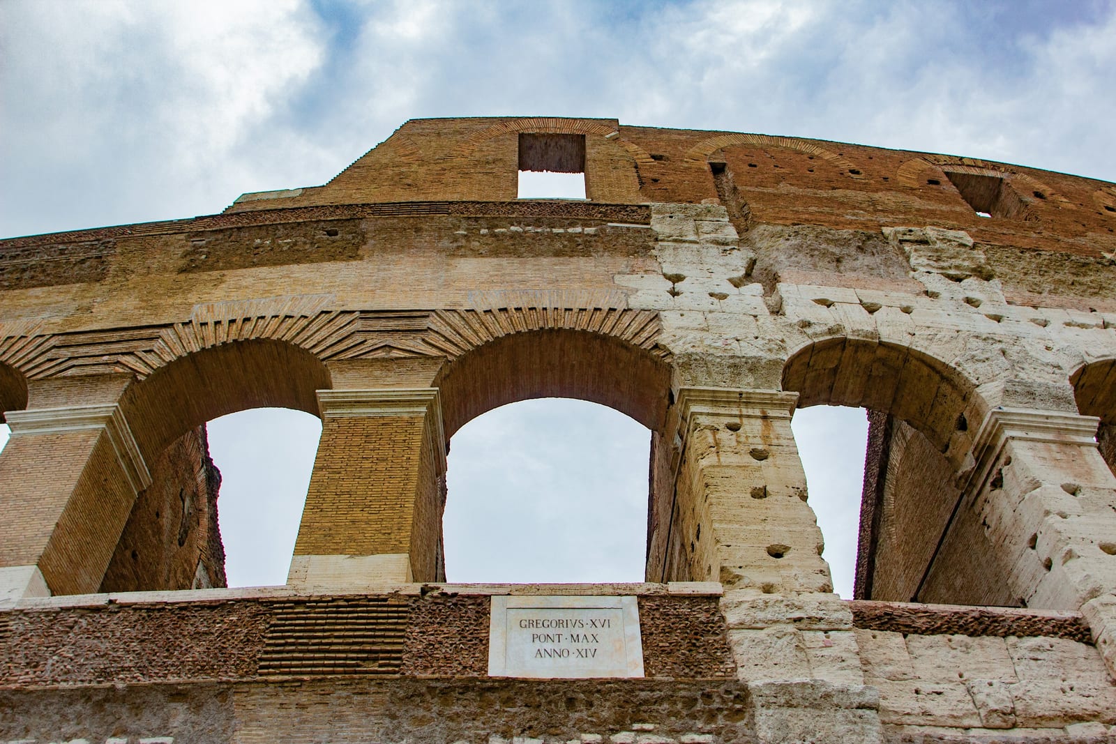 The tiered stone arches of the Colosseum against a clear sky.