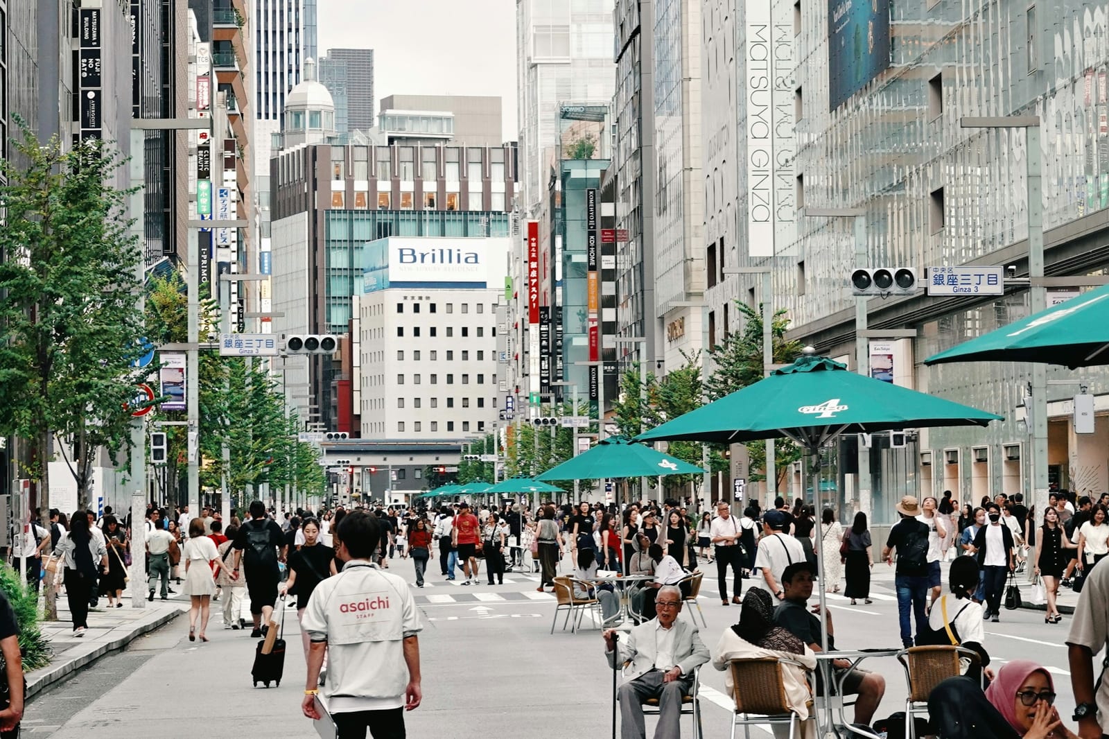 Crowds strolling Ginza's Chuo-dori on a car-free weekend, with cafe parasols set out in the road.