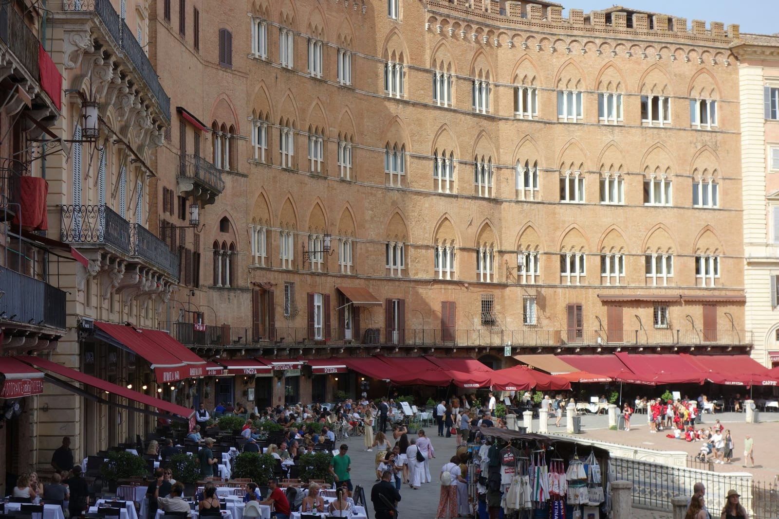 Restaurants with red awnings lining a grand Italian square, aimed squarely at tourists.