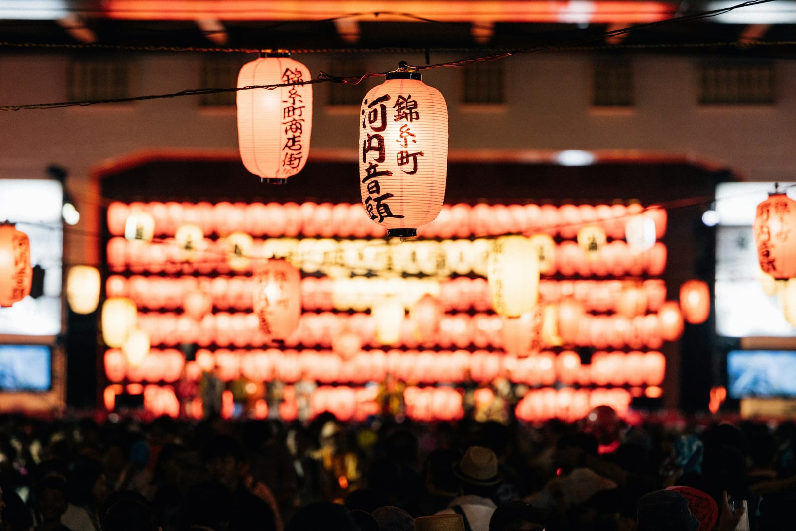 Paper lanterns strung over a free summer street festival in Tokyo at night.
