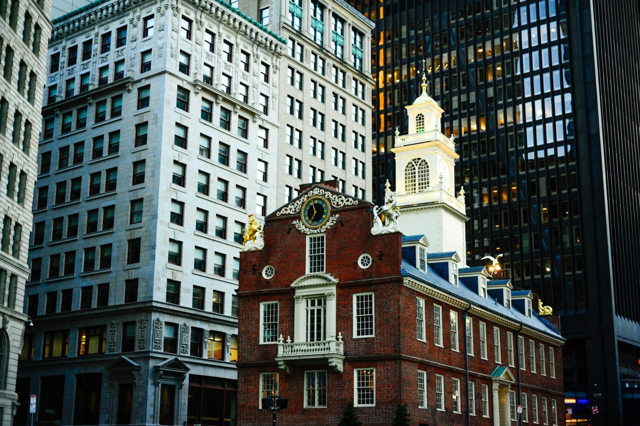 The Freedom Trail's red-brick line winds past the Old State House in downtown Boston under a bright sky.