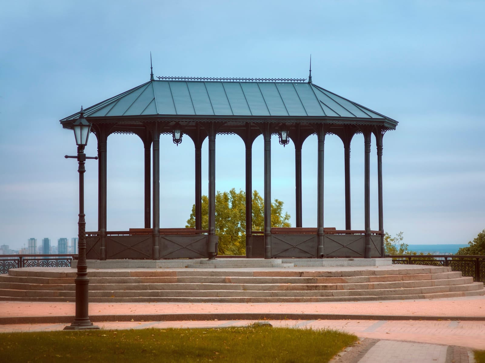 A red octagonal seaside pavilion stands on a paved waterfront with the ocean behind it.