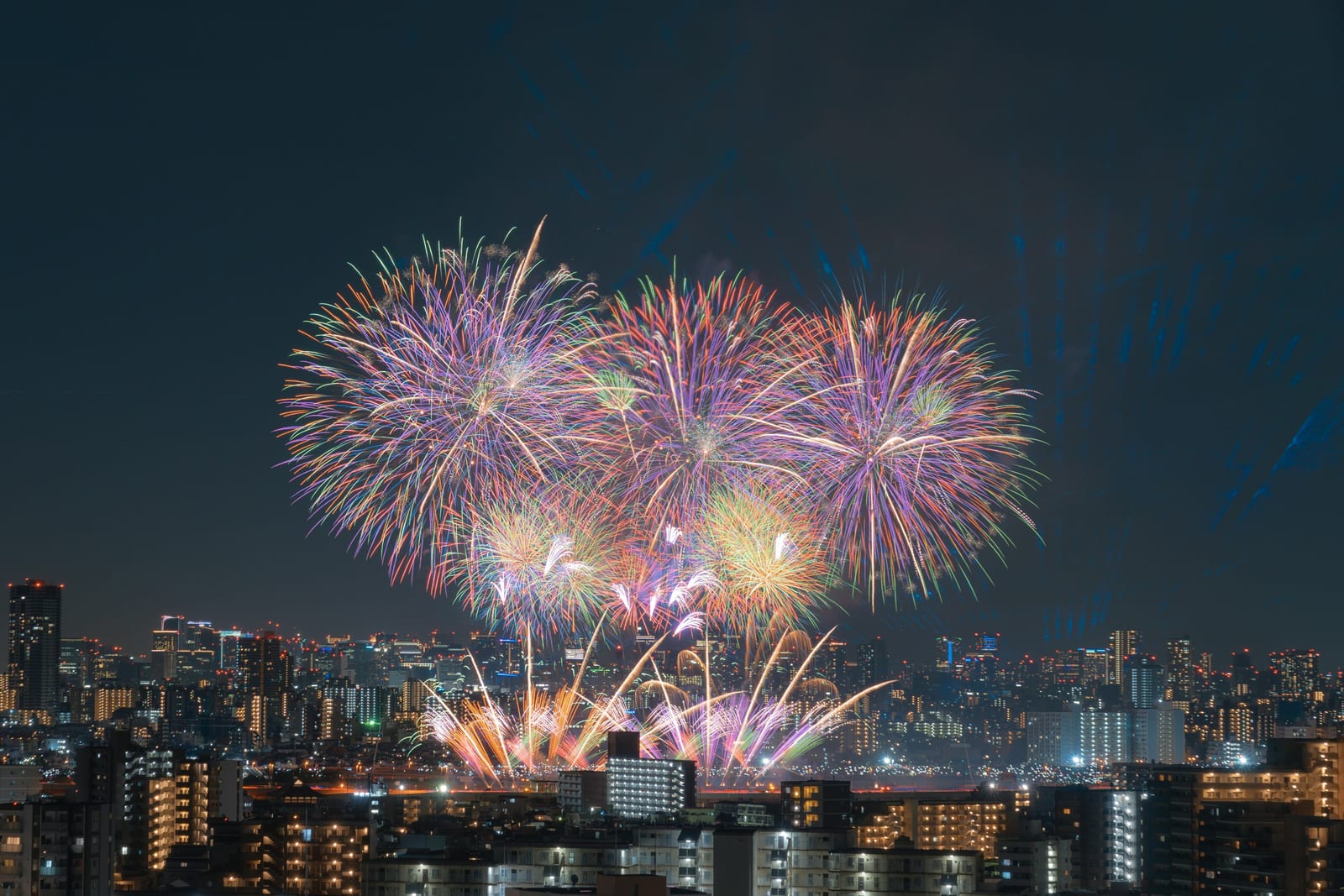 Colorful fireworks bursting over the Tokyo skyline at night.