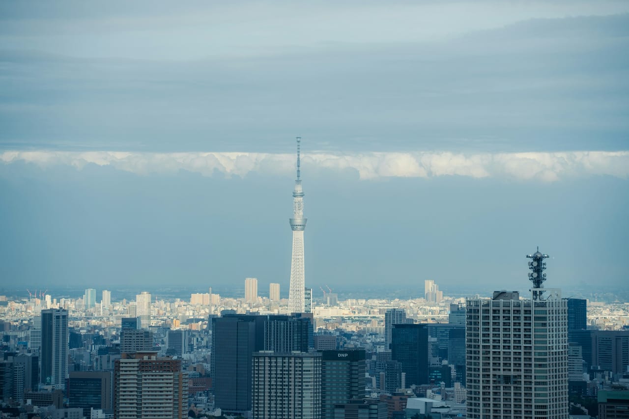 The Tokyo Skytree's pale spire rises far above the surrounding cityscape under a soft afternoon sky.