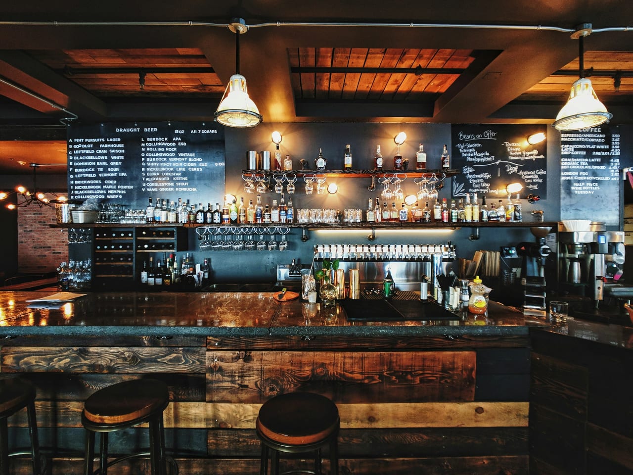 A dimly lit jazz bar with brick walls, warm lighting, and a small stage in the background.