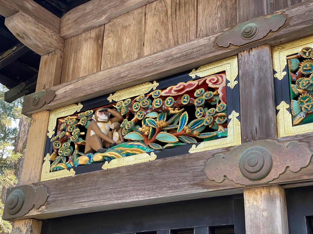 A gilded and painted monkey carving on the Sacred Stable at Nikko Toshogu, part of the shrine's famous monkey panels.