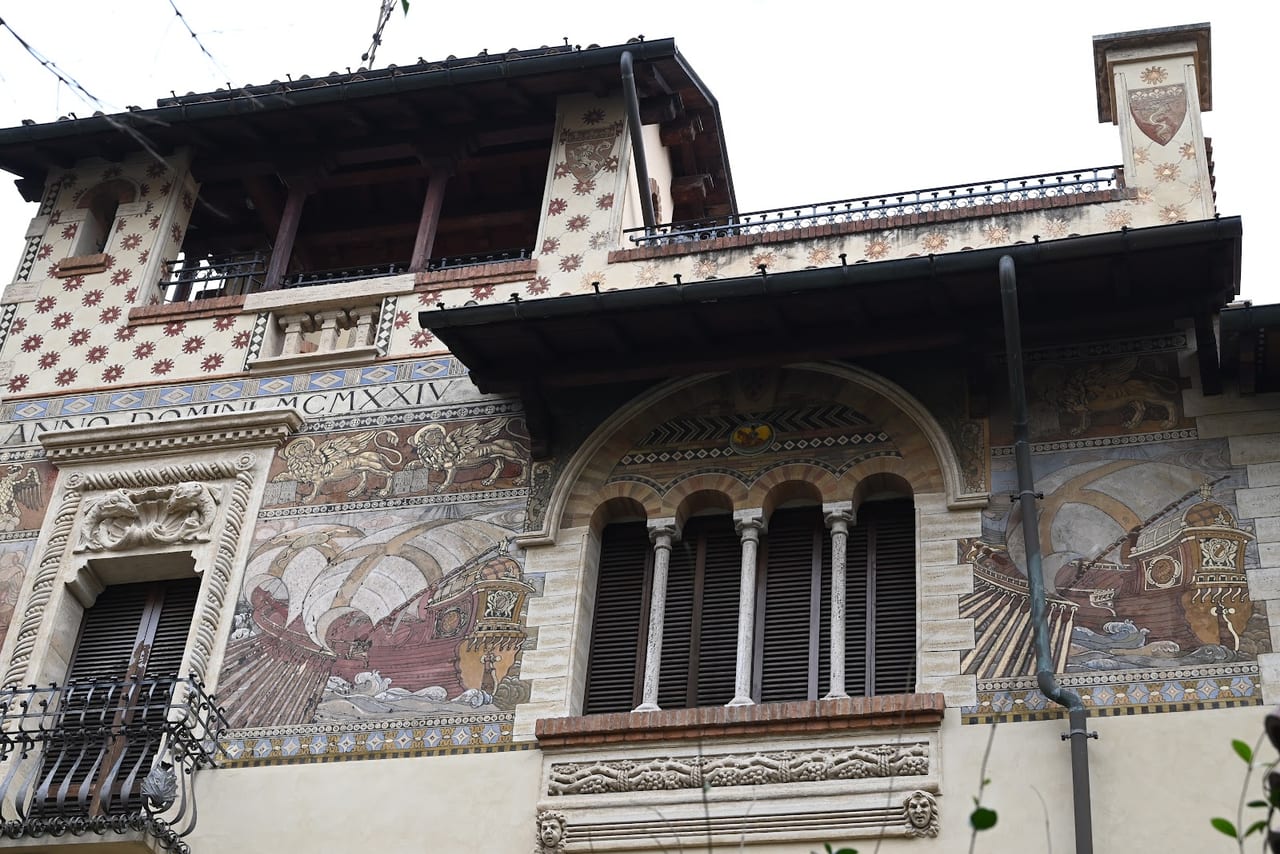 A Coppedè facade dense with mosaics of galleons and winged lions, tribune windows, and the date MCMXXIV, in the fairytale quarter.