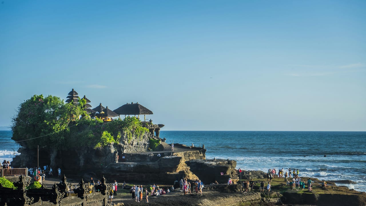 Tanah Lot temple stands on a rocky sea platform with waves and the open ocean behind it in Bali.