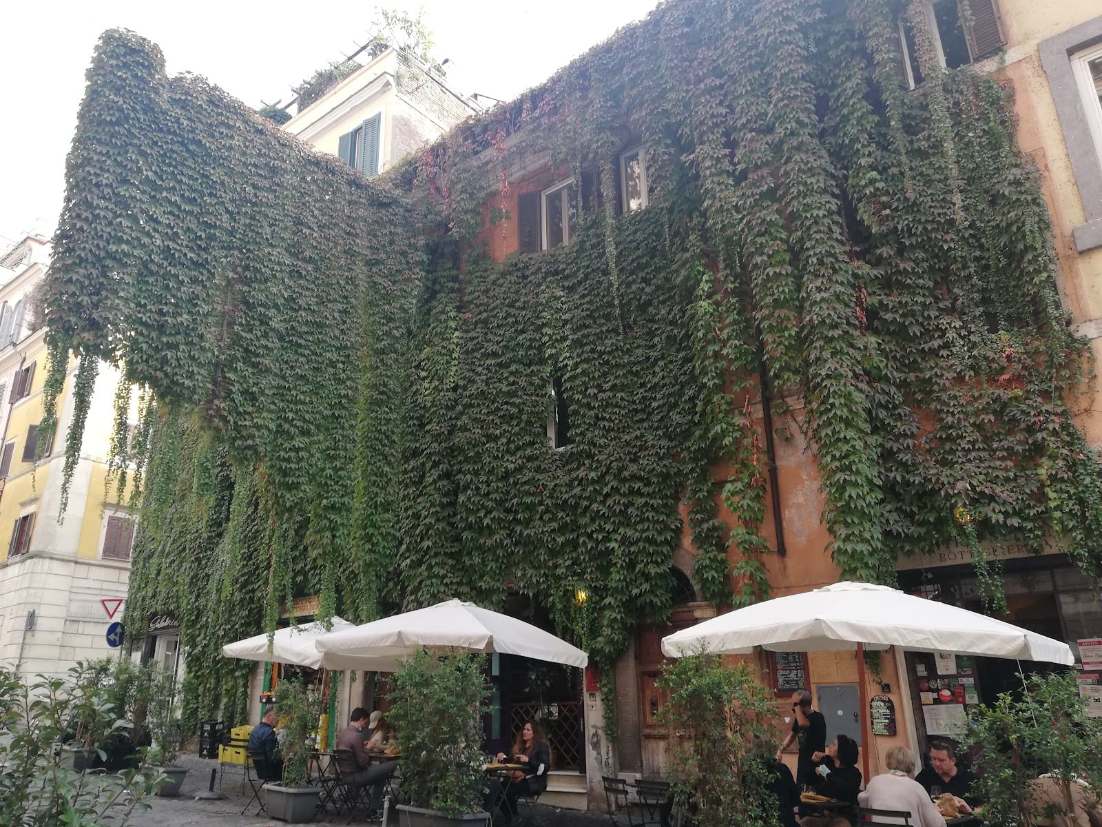 A cobblestone Monti lane with cafe stools set out along ochre buildings.